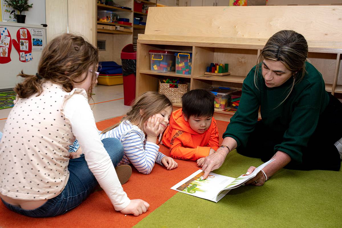 Preschool kids reading book on the floor.